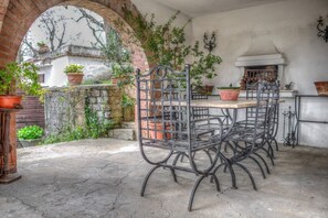 Eine Außenpatio mit einem schmiedeeisernen Tisch und Stühlen, Topfpflanzen und einer Ziegelwand.