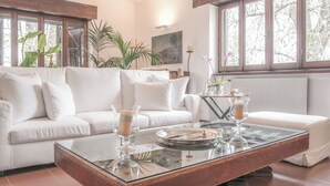 A modern living room with a white sofa, a glass coffee table, and large windows. - Il Casale dei Castagni (Caprarola)