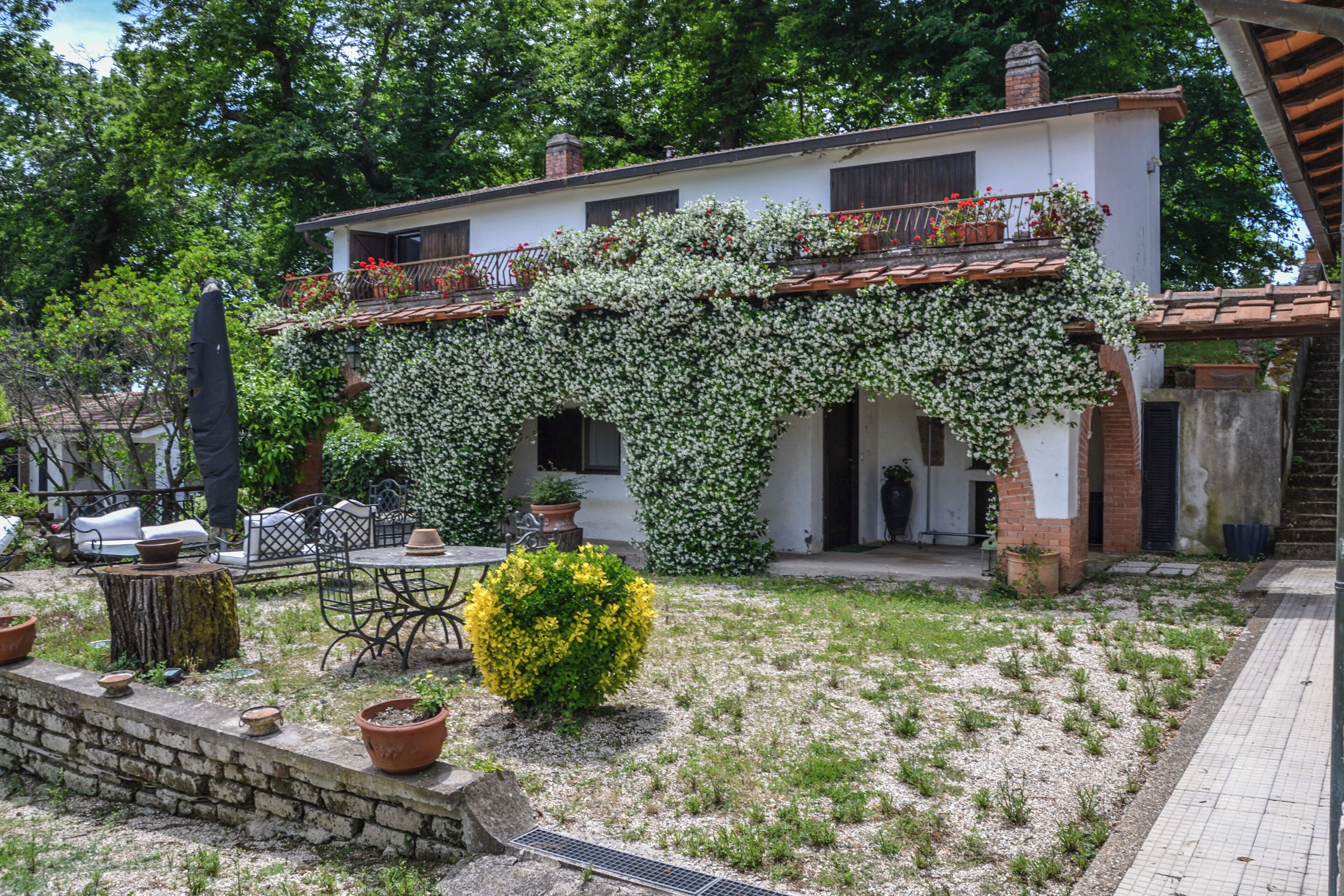 A house with a covered patio, outdoor seating, and potted plants.