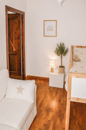 A room with a wooden door, a bedside table with a lamp and a plant, a bed with a teddy bear, and a framed picture on the wall. - Il Casale dei Castagni (Caprarola)