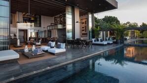 Un área de piscina moderna al aire libre con zona de comedor y asientos.