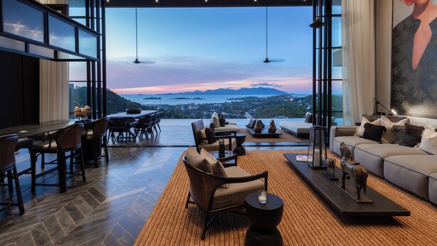 Un espacio habitable amplio con un gran ventanal que ofrece una vista panorámica, amueblado con un sofá, sillones y una mesa de centro.