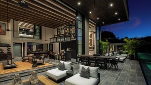Un amplio espacio exterior con varias opciones de asientos, piscina y un diseño arquitectónico moderno.