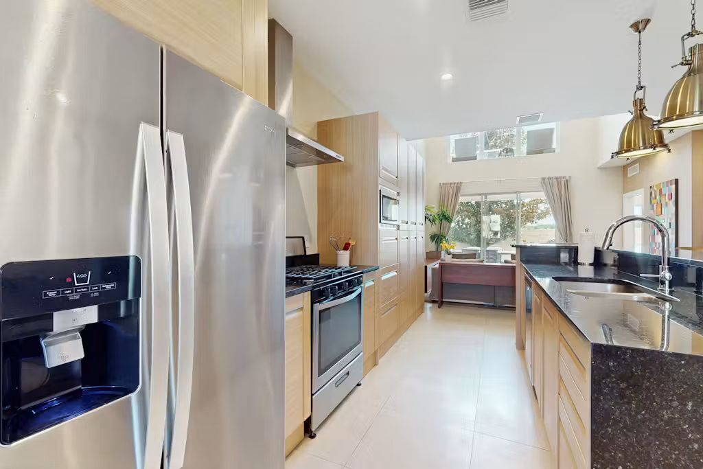A modern kitchen with stainless steel appliances, a water dispenser, and a central island.