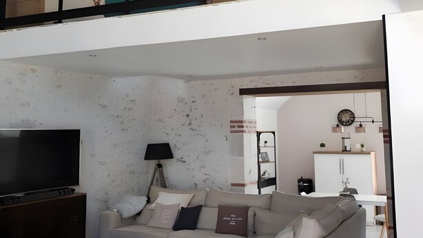 A modern living room with a sofa, coffee table, TV, and a balcony with a view.