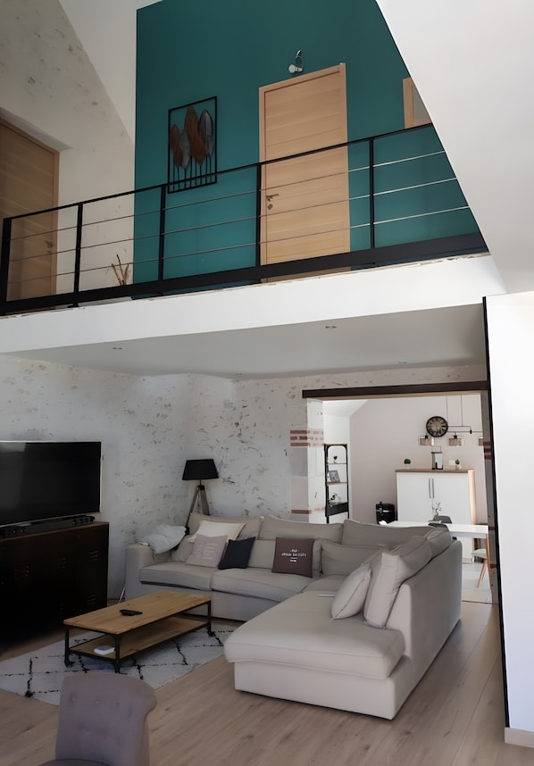 A modern living room with a sofa, coffee table, TV, and a balcony with a view.