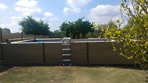 A fenced yard with a ladder leading to a wooden structure.
