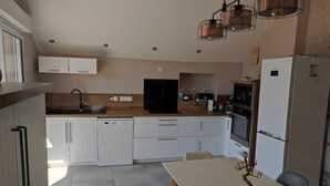 A modern kitchen with white cabinets, a dishwasher, a stove, and a refrigerator.