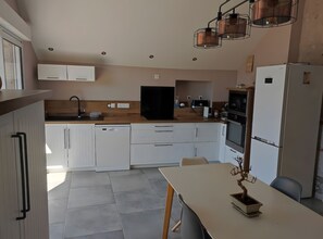 A modern kitchen with white cabinets, a dishwasher, a stove, and a refrigerator.