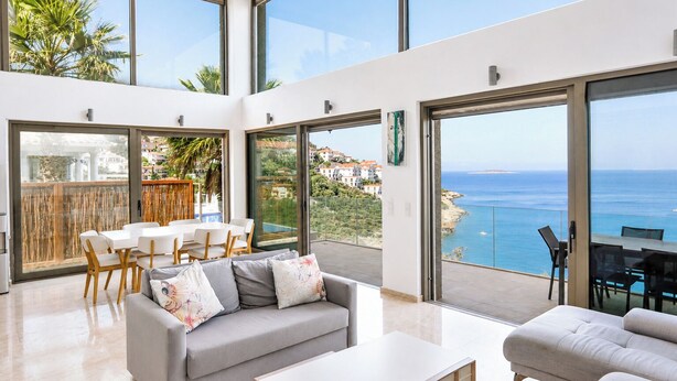 Un interior moderno con balcón vistas al mar, zona de comedor y sofá.