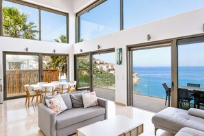 A modern interior with a balcony overlooking the sea, a dining area, and a sofa. - Villa Ayışığı (Kaş)