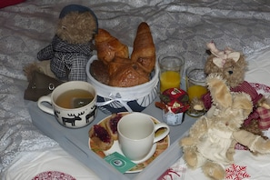 Un safata de petitdejuni amb croissants, una tassa, un got de suc i un osset de peluix.