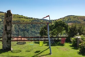 Un tobogan en una zona enjardinada amb vistes a turons ondulats.