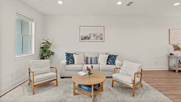 A living room with a sofa, two armchairs, a coffee table, a ceiling fan, a framed picture on the wall, and a window with blinds. - Sleeps 26 • 2 Coastal Homes • 1 Block To Beach + Pool + Hot Tub | Twin Tides (Panama City Beach)