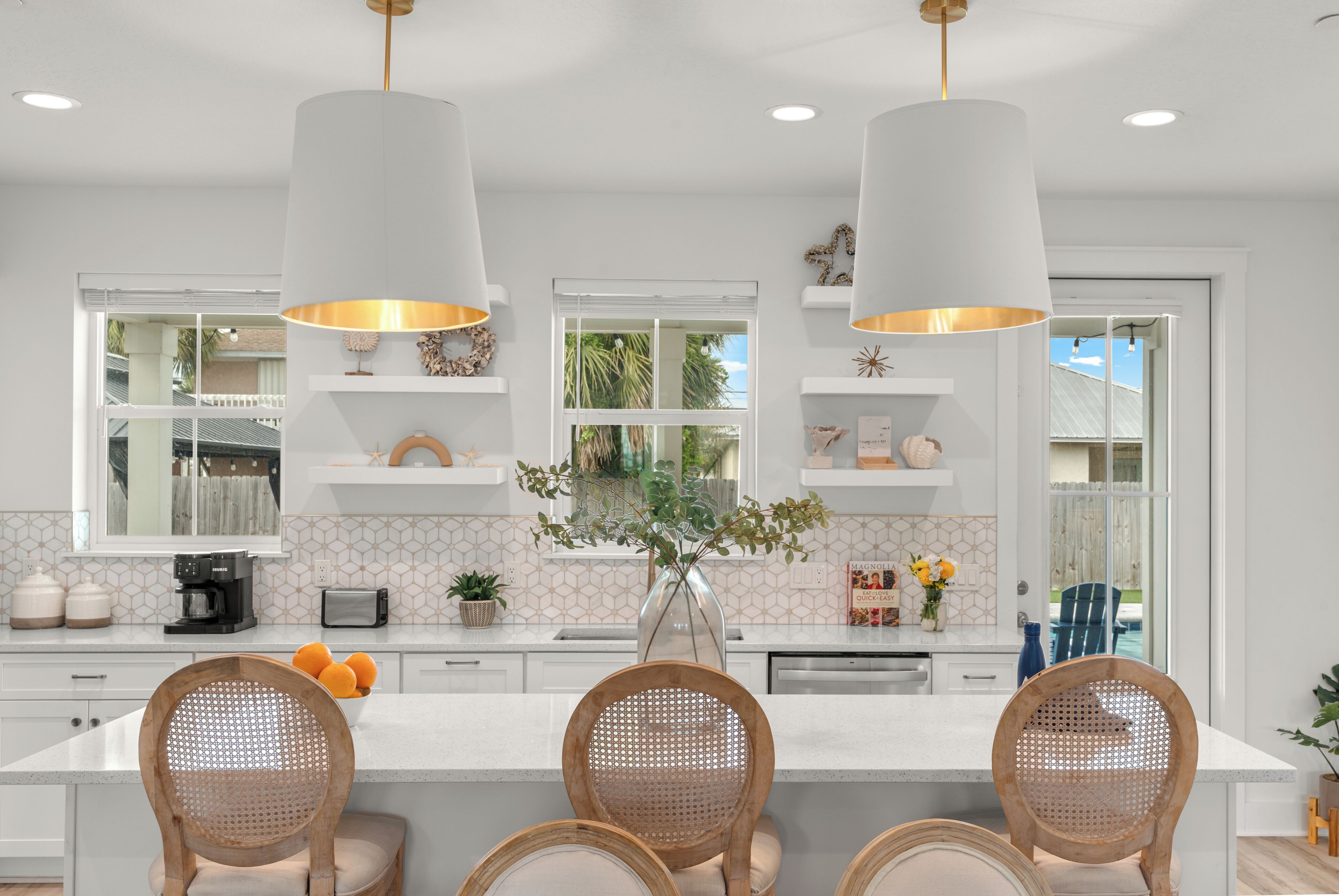 Una cocina moderna con una isla central, iluminación colgante y vistas al exterior.