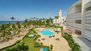 Un resort con una gran piscina, palmeras y vista al mar.
