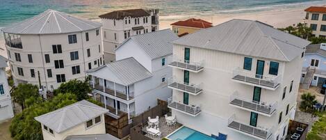 A coastal hotel with multiple buildings, a swimming pool, and a view of the ocean at sunset.