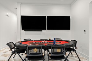 Ein Konferenzraum mit einem runden Tisch, schwarzen Stühlen und zwei großen schwarzen Bildschirmen an der Wand.