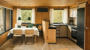 Eine kleine Küche mit Essbereich, Holzwänden und einem großen Fenster.