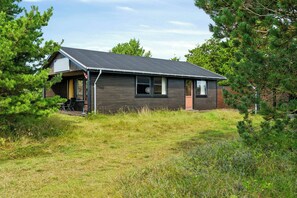 A modern house with a sloped roof, a porch, and a small deck. - Charming vintage house in North Sea nature (Ringkøbing)