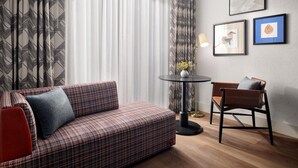 Una sala de estar moderna con un sofá a cuadros, una mesa redonda con un jarrón de flores y una silla.