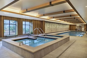 Ein großes Hallenbad mit Holzbalkendecke und einer Wand aus Stein mit geometrischem Muster.