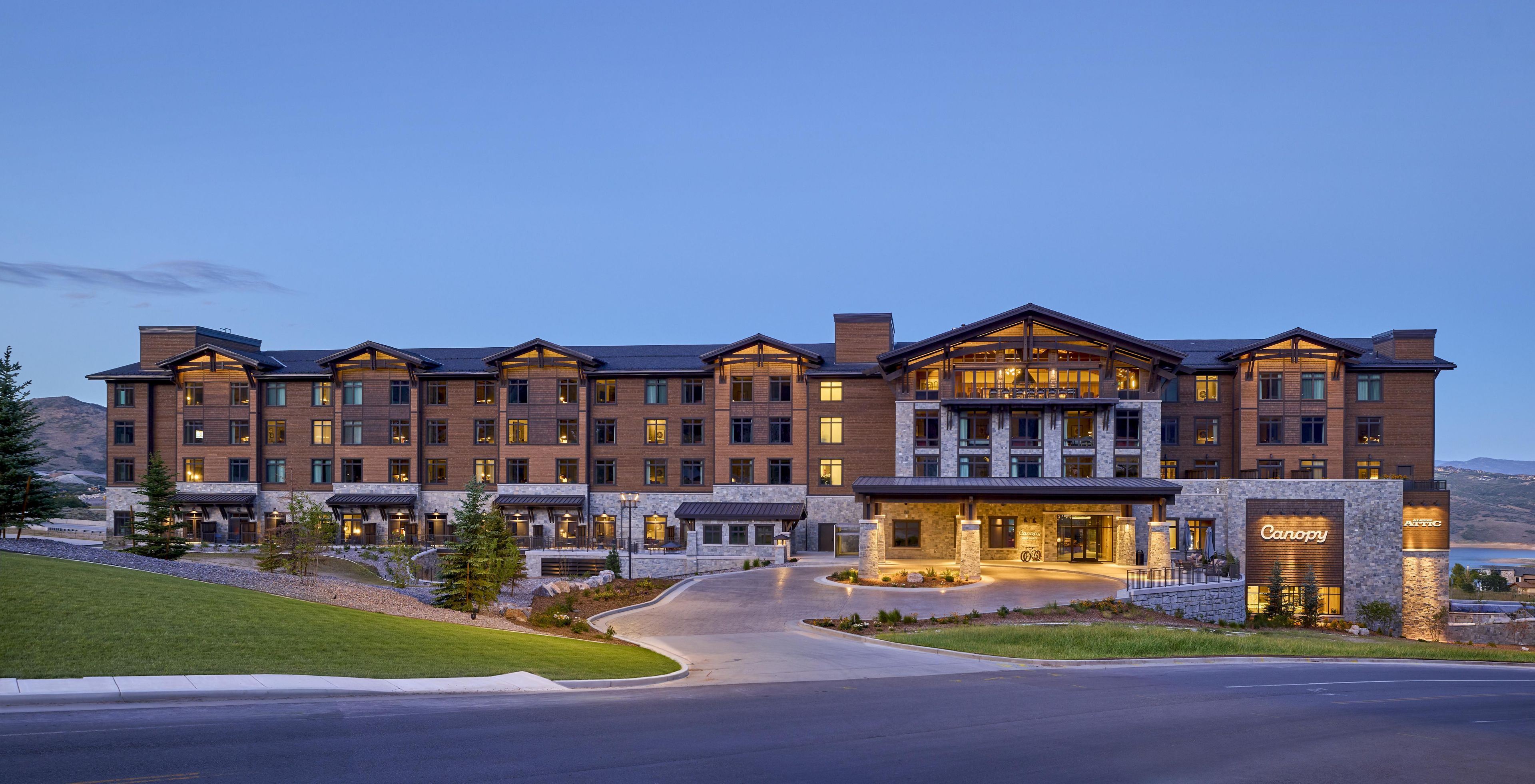 A multi-story hotel with a stone facade, large windows, and a well-lit entrance.