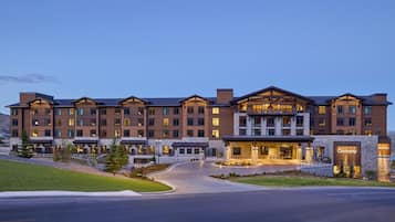 A multi-story hotel with a stone facade, large windows, and a well-lit entrance.