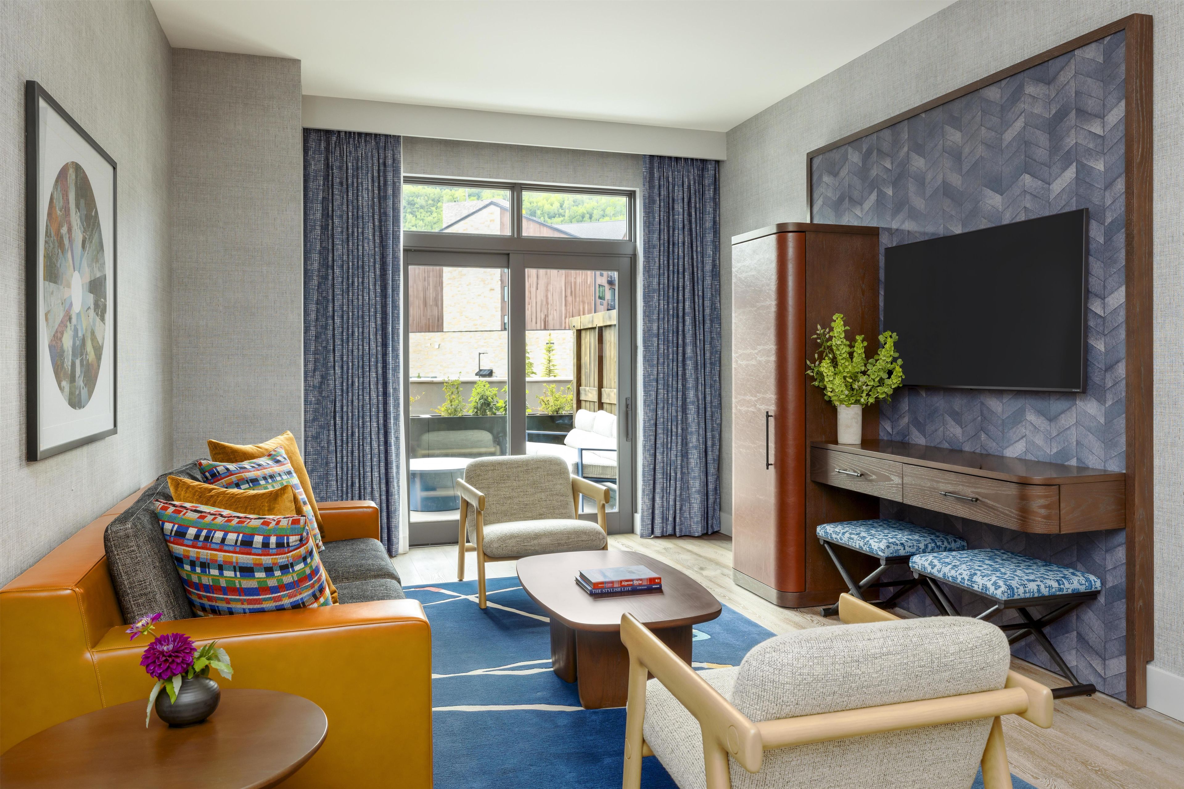 A modern living room with a sofa, armchairs, a coffee table, and a TV.