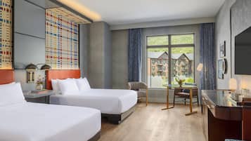 Een hotelkamer met twee bedden, een bureau, een stoel, een raam met uitzicht op gebouwen en een kamer met een patroon op de muur.