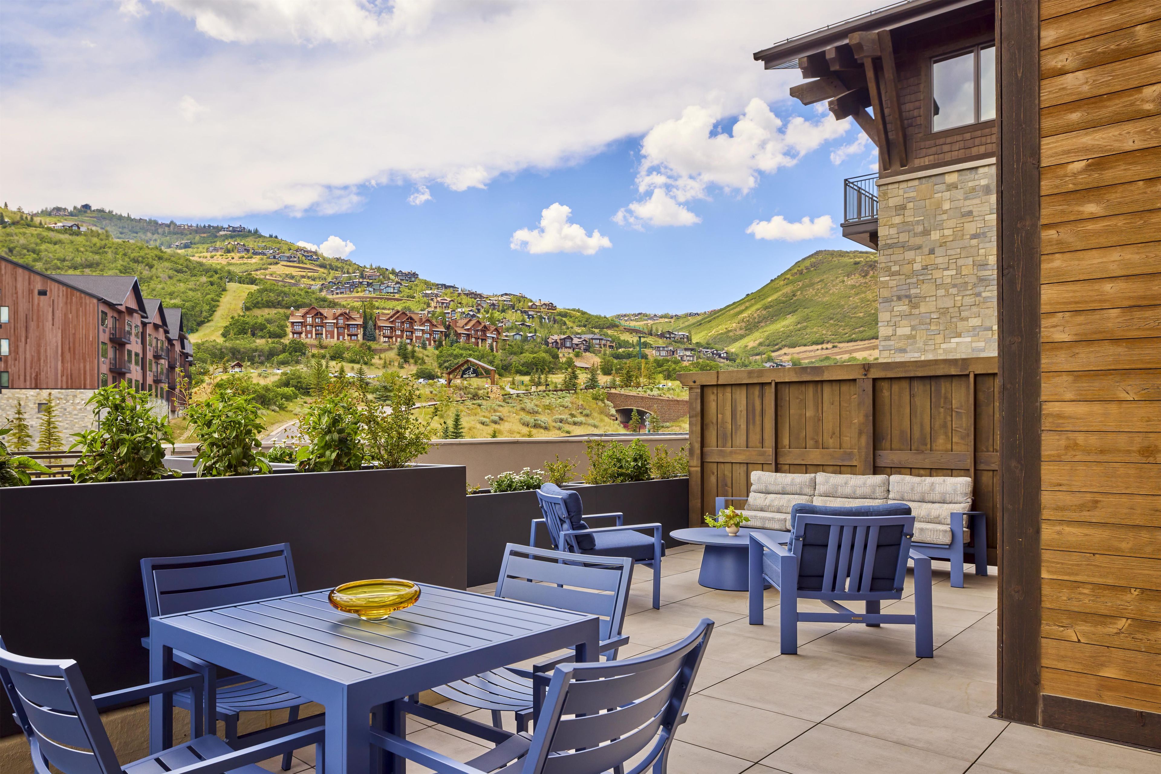 A patio with outdoor seating and a view of a hillside community.