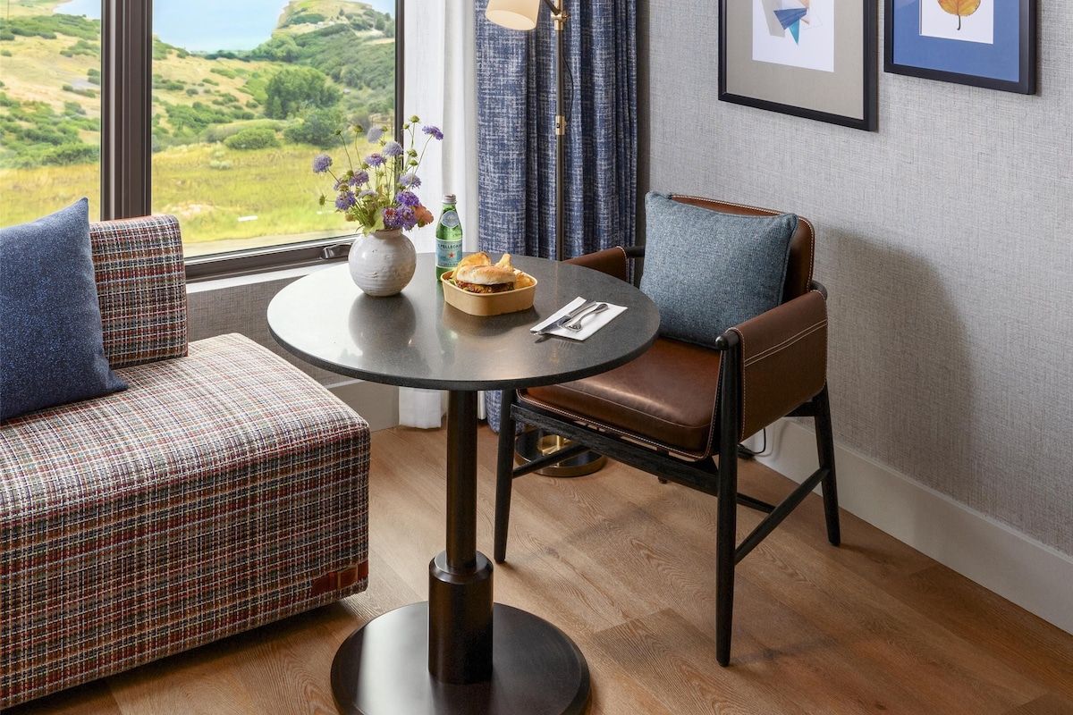 Una habitación con vista a un lago, una mesa de comedor con un jarrón de flores y dos cuadros en la pared.