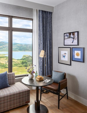 Una habitación con vista a un lago, una mesa de comedor con un jarrón de flores y dos cuadros en la pared.