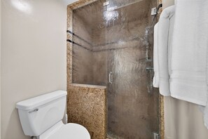 A bathroom with a toilet, a shower enclosure, and a towel rack.