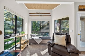 Ein modernes Wohnzimmer mit großen Fenstern, Holzboden, einer Ledersofa und einer integrierten Bank mit Blick ins Freie.
