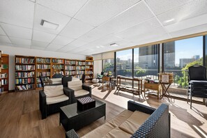 Eine großzügige Bibliothek mit hohen Decken, großen Fenstern und zahlreichen Bücherregalen voller Bücher.