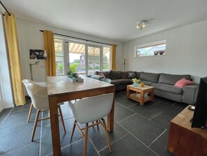 Ein modernes Wohnzimmer mit Essbereich, einer Couch und einem kleinen Tisch mit Pflanzen.