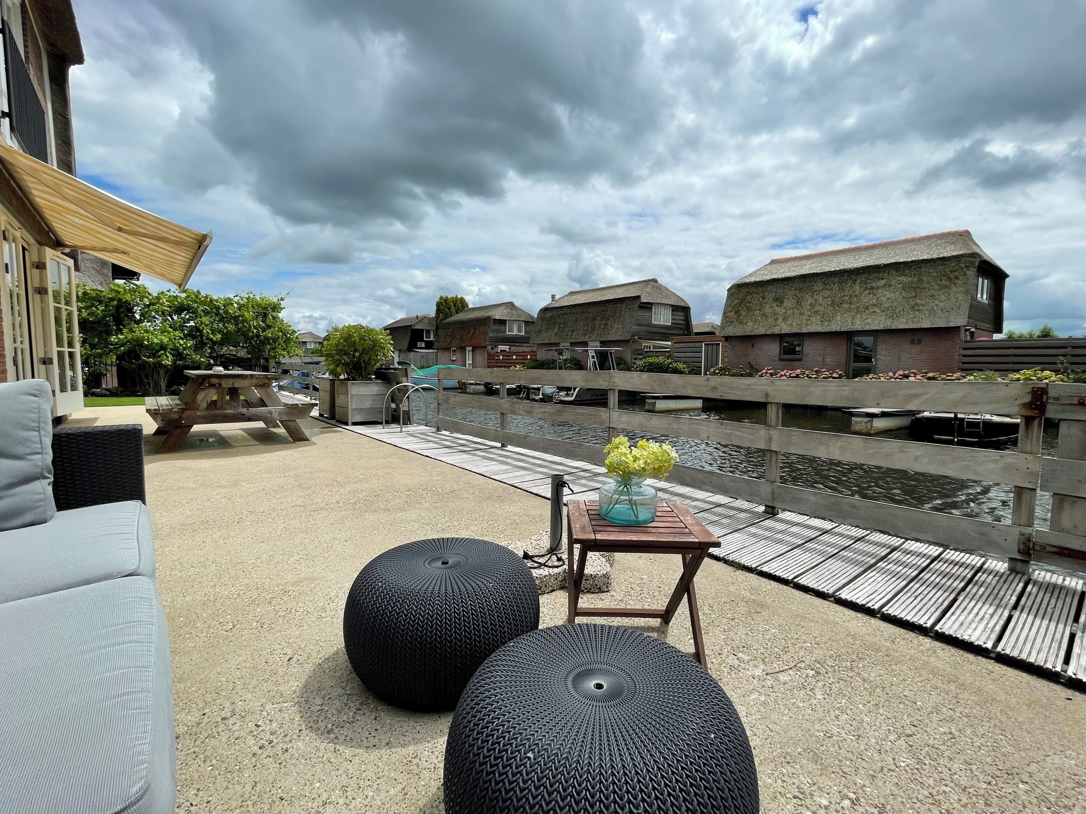 Un patio con posti a sedere all'aperto, un tavolo in legno con un vaso e vista sull'acqua e case tradizionali.