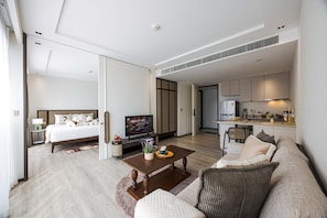 Ein modernes Hotelzimmer mit Bett, Fernseher, Essbereich und Küche.