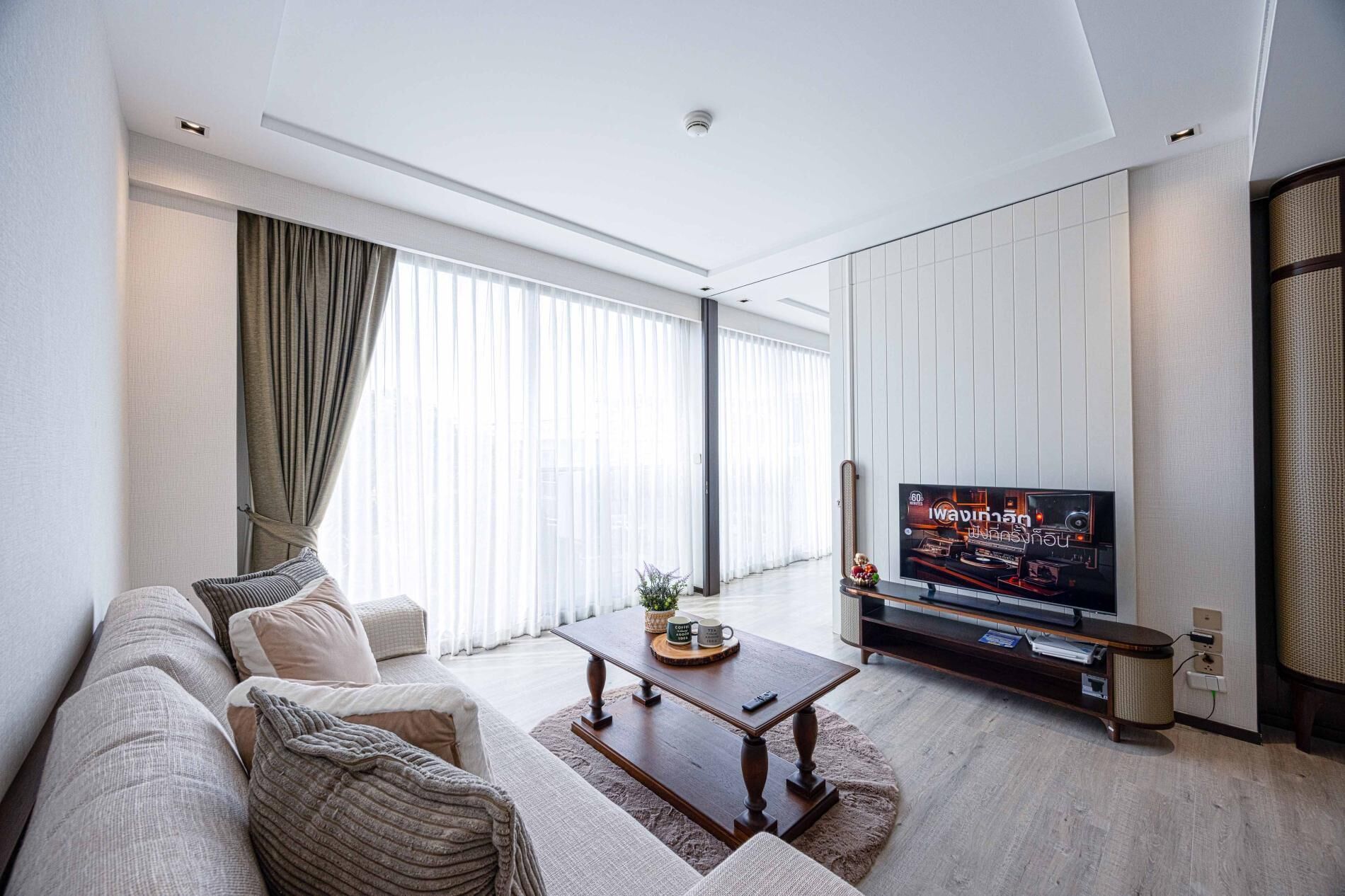Una sala de estar moderna con un sofá, una mesa de centro y un televisor de pantalla plana sobre un mueble.