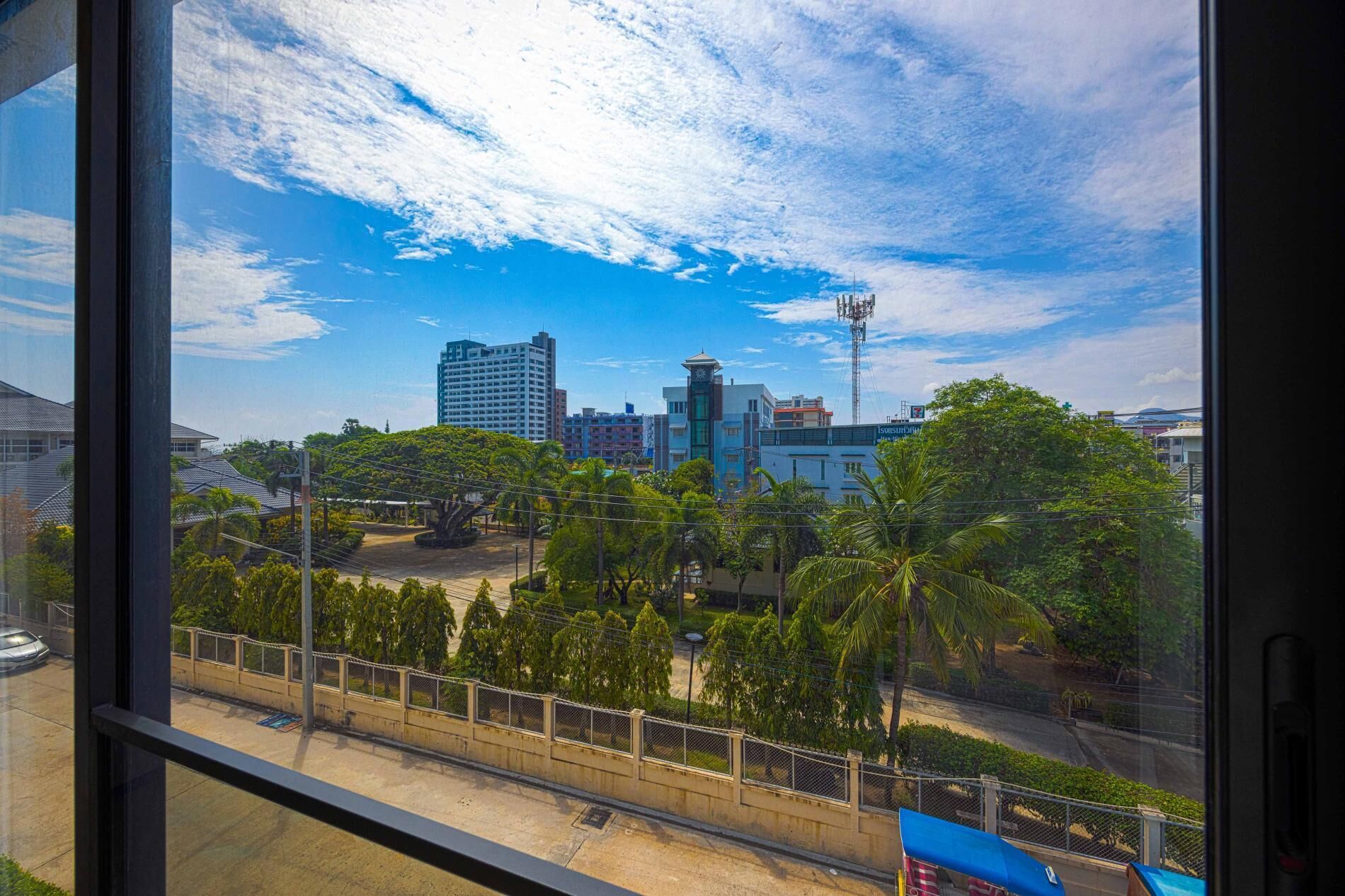 Paisagem urbana com edifícios modernos, um campanário e céu azul límpido.