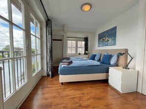 A bedroom with a bed, bedside tables, a nightstand, a window with a view of the water, and a painting on the wall. - Luxury holiday home for 6 guests featuring a spacious waterfront terrace, a private swimming ladder, and its own mooring dock. (Breukelen)