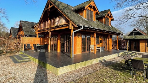 Un lodge in legno con un portico coperto, posti a sedere all'aperto e vista sul paesaggio circostante.