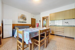 Eine kleine Küche mit Holzausstattung, einem Esstisch mit Stühlen und einem Kühlschrank.