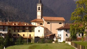 Ein Gebäude mit einem Glockenturm, umgeben von anderen Gebäuden und einer Bergkulisse.