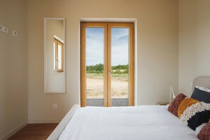 Ein Schlafzimmer mit einem großen Bett, einem Spiegel und einer Glastür, die zu einem Außenbereich führt.