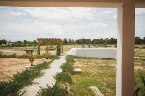 A garden with a pergola, a pool, and lounge chairs.