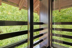 A wooden balcony with a view of dense green foliage. - Apartment 'Casa Serena&Giacomo 10' with Mountain View, Shared Garden and Wi-Fi (Bezzecca)