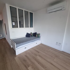 Habitació amb un llit, una finestra i un aparell d'aire condicionat.