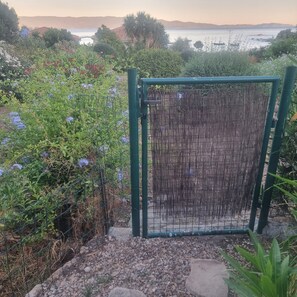 Una porta amb una pantalla de bambú, envoltada de vegetació exuberanta i amb vista al mar.